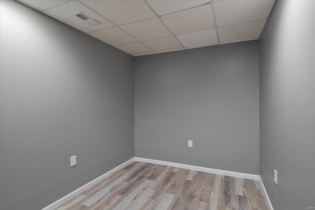 unfurnished room with light wood-type flooring, a paneled ceiling, visible vents, and baseboards