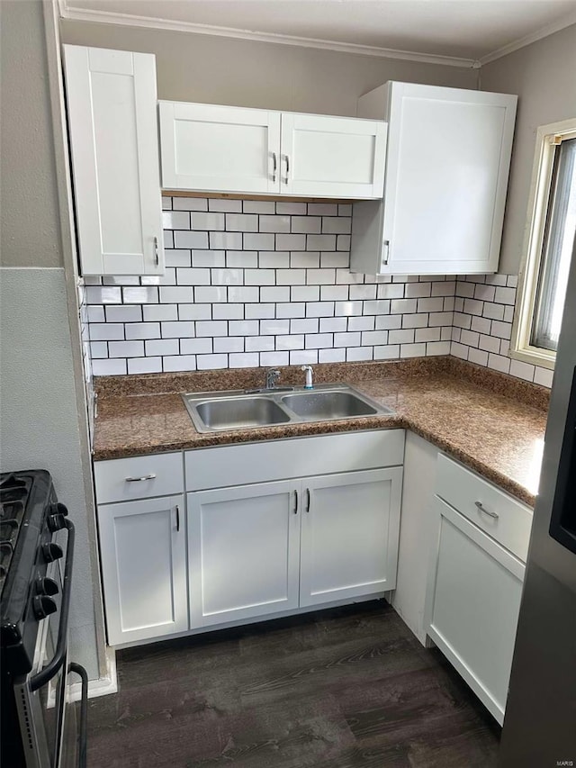 kitchen with dark countertops, a sink, white cabinetry, and range with gas stovetop