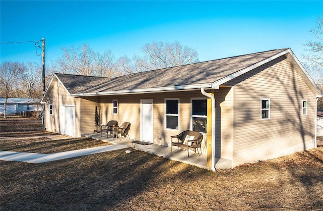 rear view of property with a patio and roof with shingles