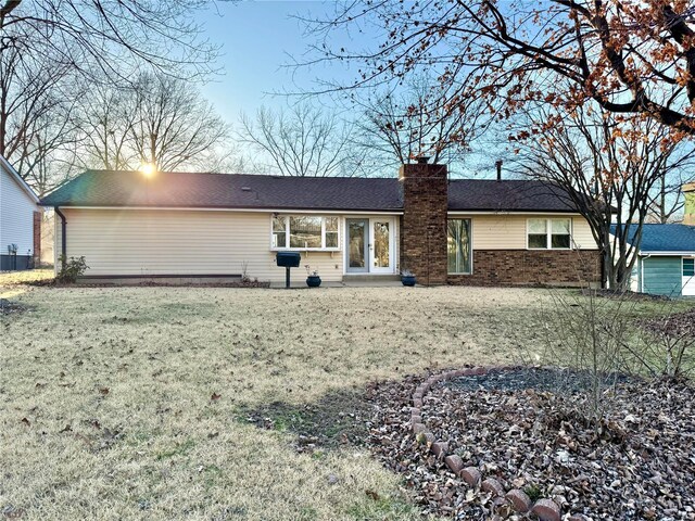 ranch-style house featuring a yard, brick siding, and a chimney