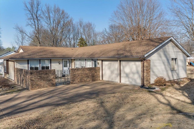 view of front of house featuring a shingled roof, concrete driveway, a garage, a fenced front yard, and brick siding