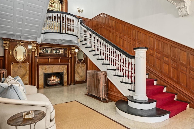 stairway featuring a premium fireplace, wainscoting, and wooden walls