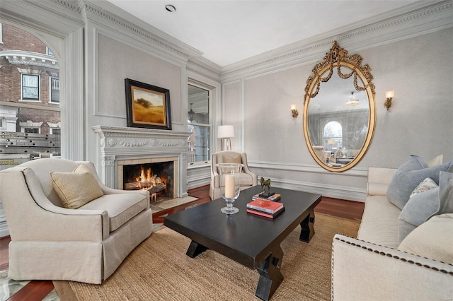 living room featuring wood finished floors, crown molding, baseboards, and a premium fireplace