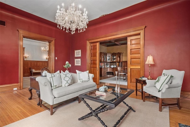 living area featuring wood finished floors, visible vents, and a notable chandelier