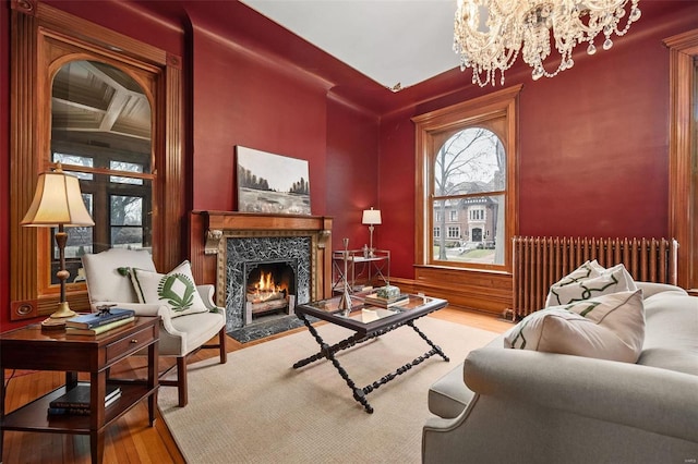 sitting room featuring a chandelier, a high end fireplace, radiator, and wood finished floors