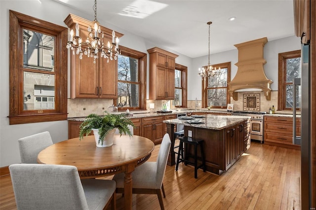 kitchen with premium range hood, decorative backsplash, high end stove, and an inviting chandelier