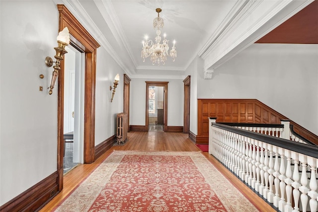 entryway with crown molding, light wood finished floors, radiator heating unit, and an inviting chandelier