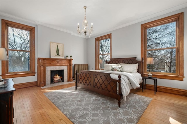 bedroom with wood-type flooring, ornamental molding, baseboards, and a high end fireplace