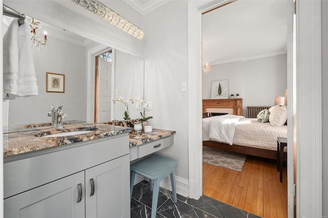 bathroom featuring crown molding, vanity, wood finished floors, a chandelier, and baseboards