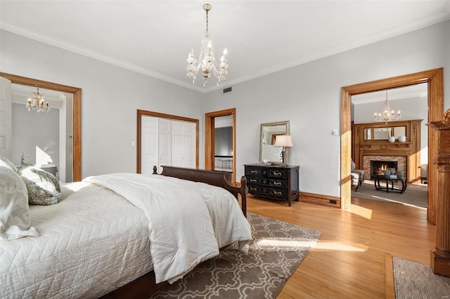 bedroom featuring a warm lit fireplace, visible vents, and an inviting chandelier