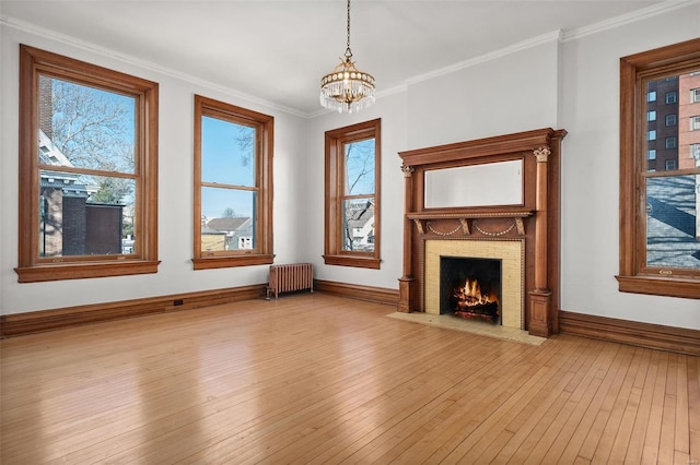 unfurnished living room featuring ornamental molding, radiator heating unit, light wood-type flooring, and a fireplace