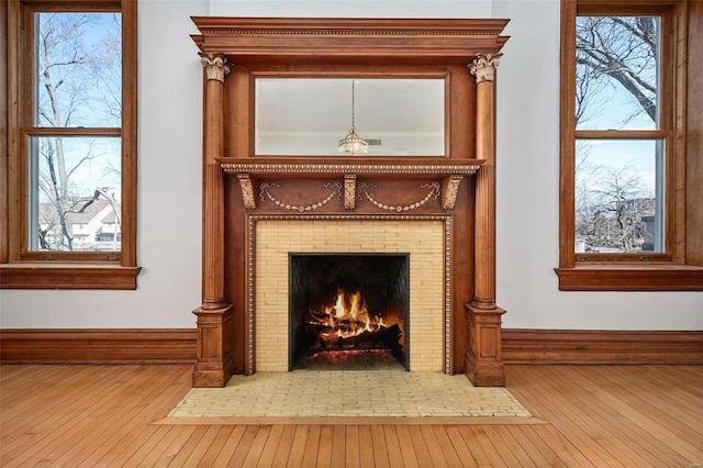 details with baseboards, a tiled fireplace, and wood finished floors