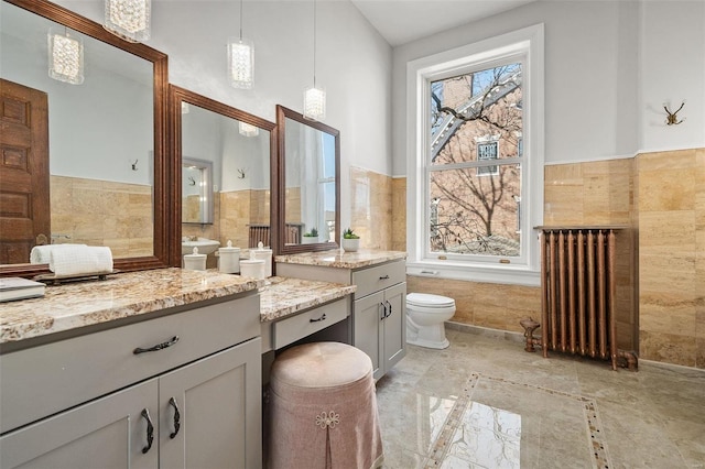 full bathroom with toilet, tile walls, radiator heating unit, and vanity