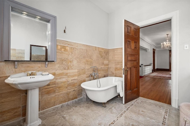 full bathroom with a freestanding bath, tile walls, and a notable chandelier