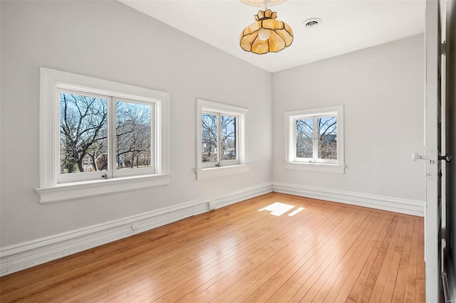 spare room featuring visible vents, light wood-style flooring, and baseboards