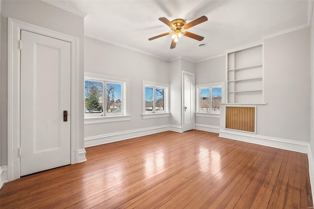 spare room featuring baseboards, ornamental molding, wood-type flooring, and a healthy amount of sunlight