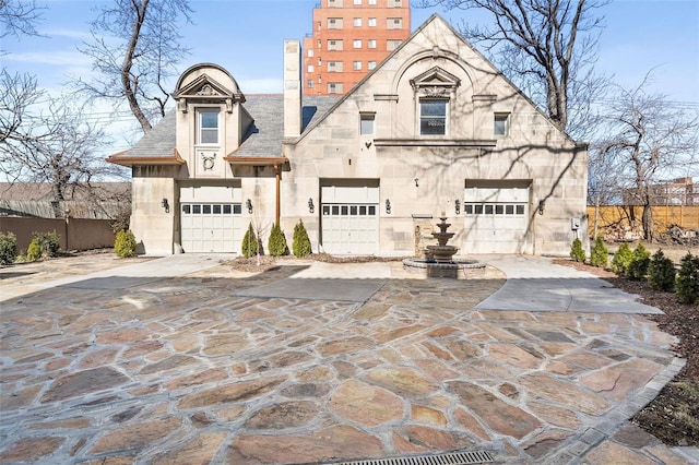 view of front of home featuring a garage, stone siding, fence, and concrete driveway