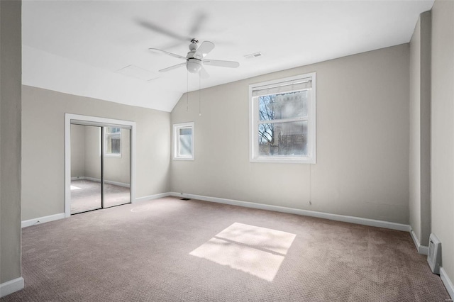 unfurnished bedroom featuring carpet floors, lofted ceiling, a closet, and baseboards