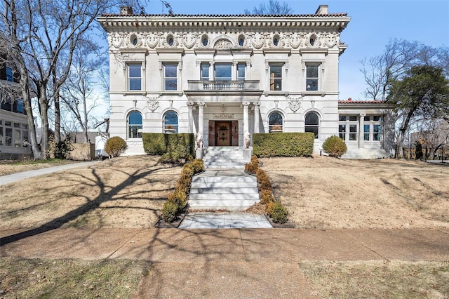 italianate-style house with a chimney and a balcony