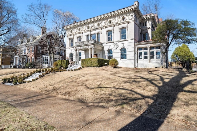 italianate house with a balcony, a chimney, a garage, and fence