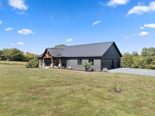 view of front of property featuring driveway, a garage, metal roof, a standing seam roof, and a front yard