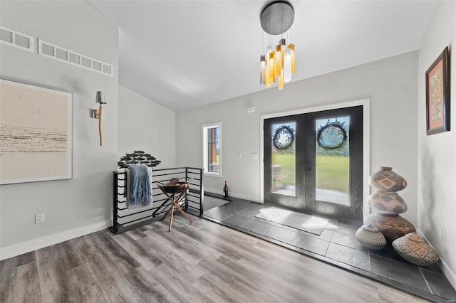 foyer with baseboards, visible vents, wood finished floors, french doors, and a notable chandelier