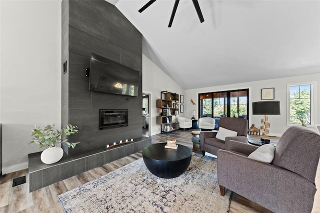 living room with baseboards, a healthy amount of sunlight, light wood-style flooring, and a tiled fireplace