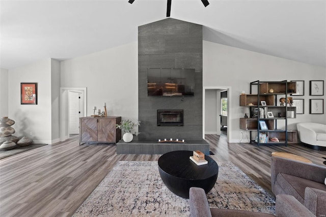 living room featuring high vaulted ceiling, a tile fireplace, wood finished floors, a ceiling fan, and baseboards