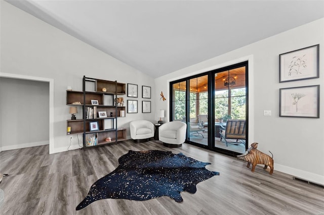 living area featuring french doors, visible vents, wood finished floors, high vaulted ceiling, and baseboards