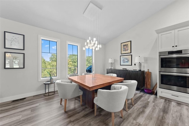 dining area featuring baseboards, visible vents, an inviting chandelier, vaulted ceiling, and light wood-type flooring