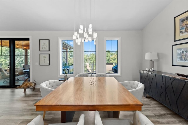 dining room with a chandelier, vaulted ceiling, plenty of natural light, and light wood-style flooring