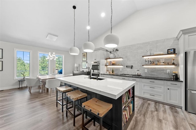 kitchen with an island with sink, dark stone countertops, and open shelves