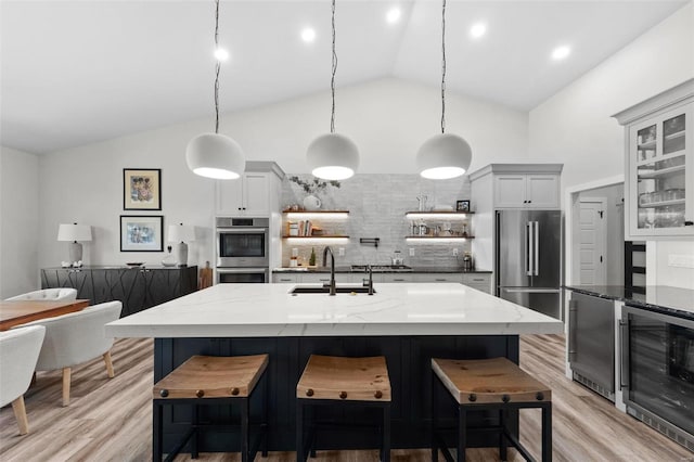 kitchen featuring glass insert cabinets, beverage cooler, decorative light fixtures, and appliances with stainless steel finishes