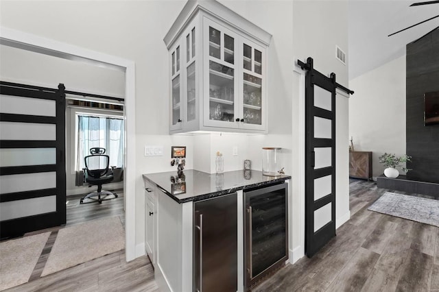 bar featuring beverage cooler, a barn door, dark wood-style floors, and refrigerator