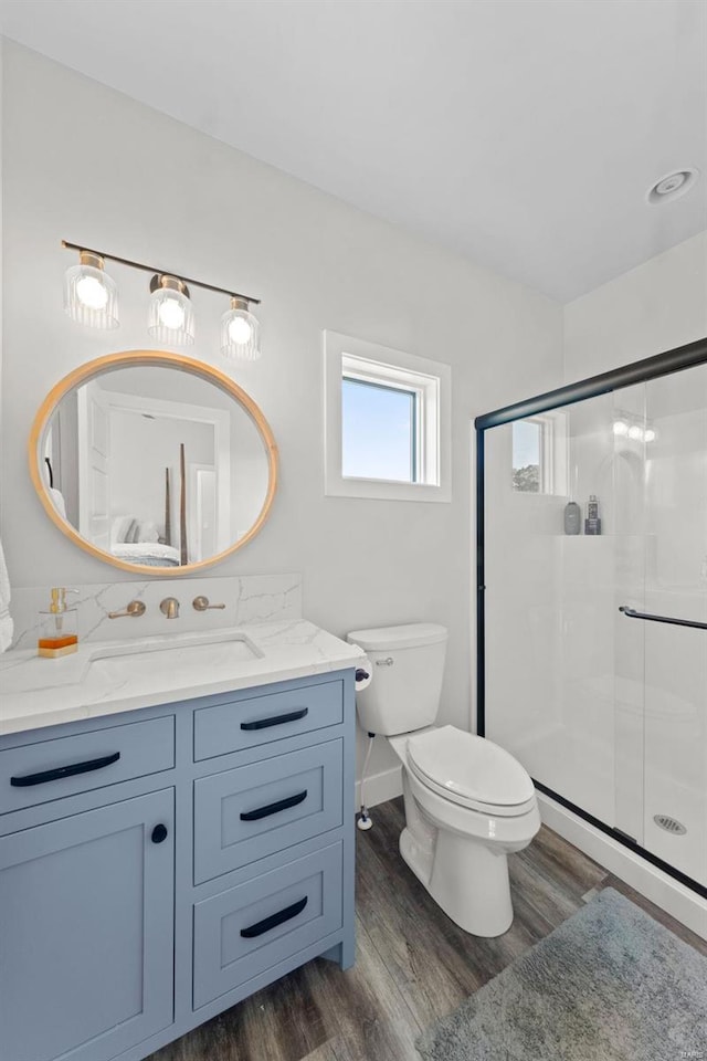 full bathroom with a stall shower, vanity, toilet, and wood finished floors