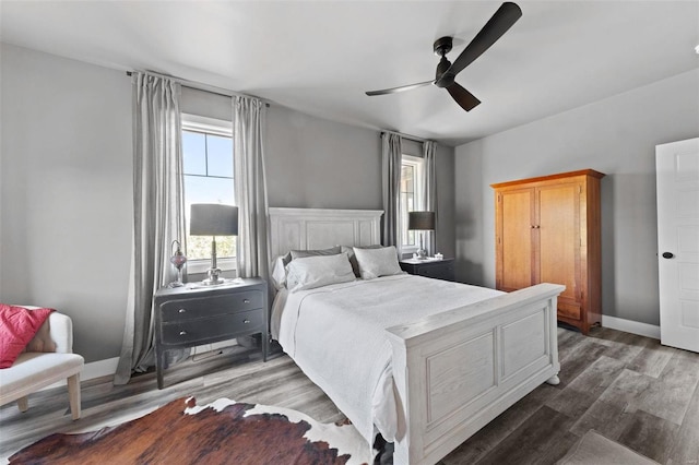 bedroom with ceiling fan, dark wood finished floors, and baseboards