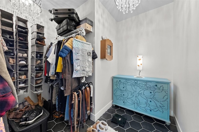 spacious closet with a chandelier and dark tile patterned floors