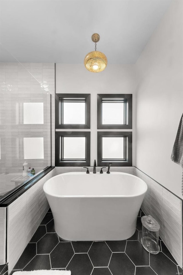 full bath with a wainscoted wall, a freestanding bath, tile walls, and tile patterned floors