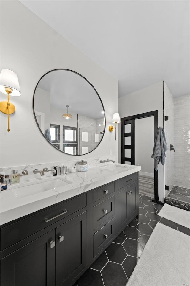 full bath featuring double vanity, a shower stall, a sink, and tile patterned floors