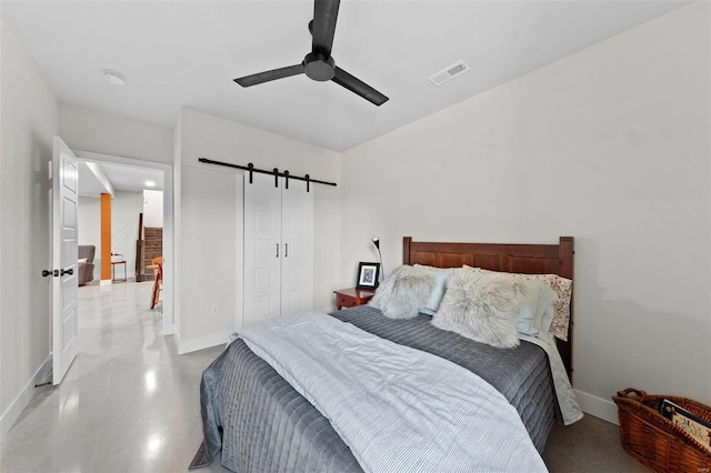 bedroom featuring a closet, visible vents, a barn door, a ceiling fan, and baseboards