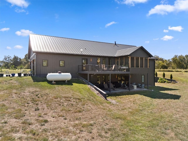 rear view of house with metal roof, a patio area, a lawn, and a standing seam roof