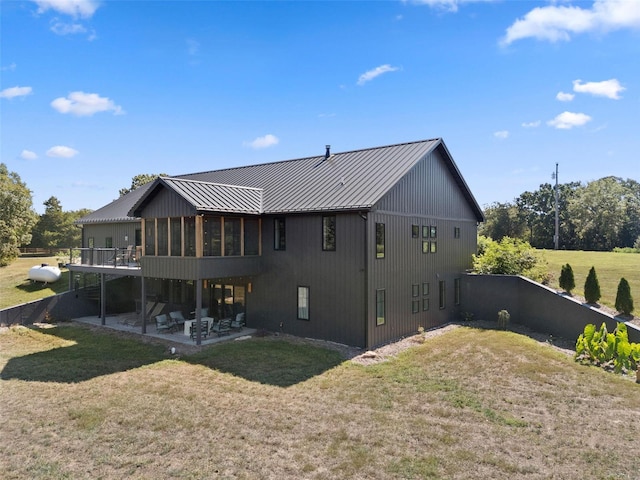 back of house with a patio, a sunroom, metal roof, a standing seam roof, and a yard