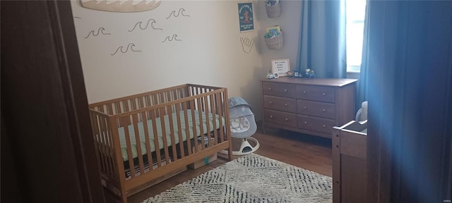 bedroom featuring a crib and wood finished floors