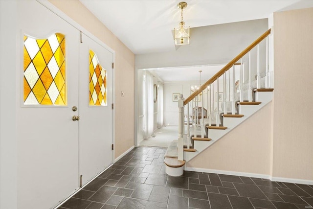 entrance foyer with baseboards, stone finish flooring, and stairway