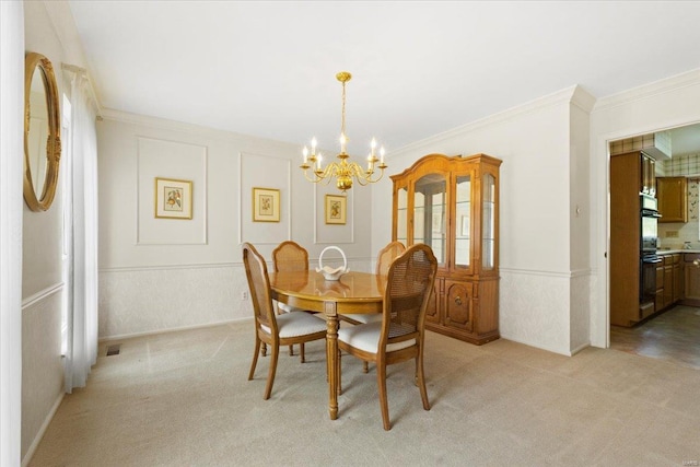 dining space featuring ornamental molding, wainscoting, a decorative wall, light colored carpet, and a chandelier