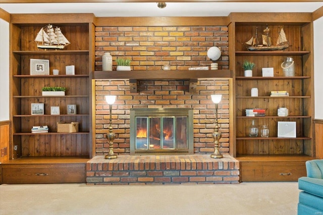 living area with carpet flooring, wainscoting, a brick fireplace, and wood walls