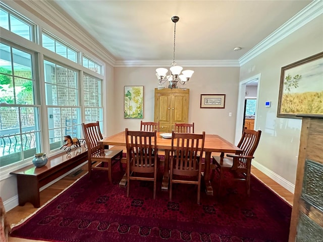 dining room featuring ornamental molding, a chandelier, baseboards, and wood finished floors