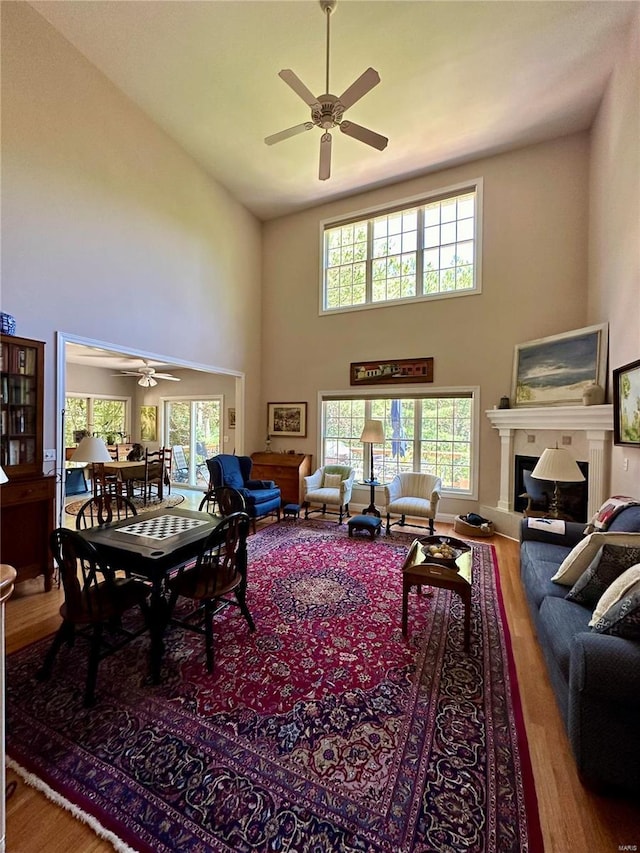 living area with a fireplace, high vaulted ceiling, and wood finished floors