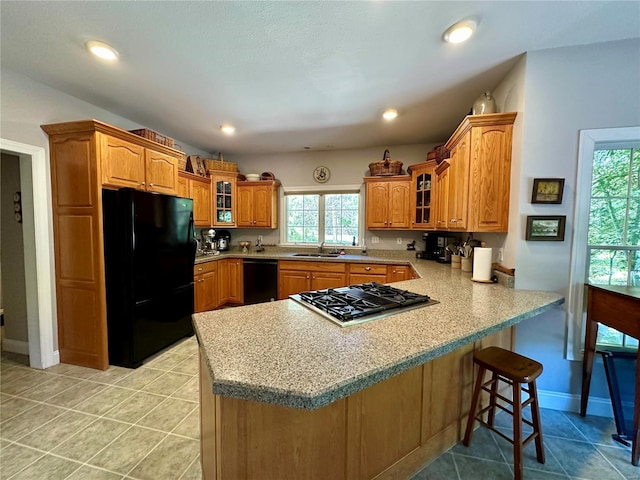 kitchen featuring glass insert cabinets, light countertops, a peninsula, and black appliances