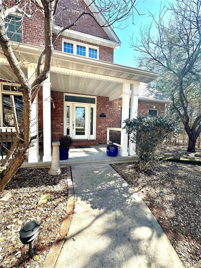 entrance to property with covered porch and brick siding